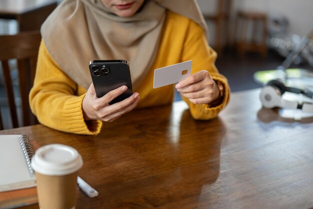 Une femme musulmane utilisant sa banque mobile ou enregistrant sa carte de crédit sur une plateforme d'achat