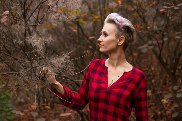 Femme mystérieuse aux cheveux courts sur fond de forêt d'automne avec des arbres desséchés