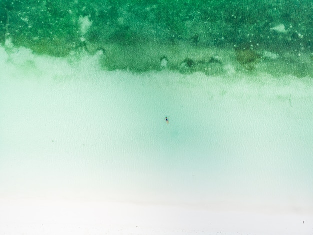 Femme nageant dans l'eau transparente turquoise de la mer des Caraïbes. Vue aérienne du haut vers le bas, composition minimale