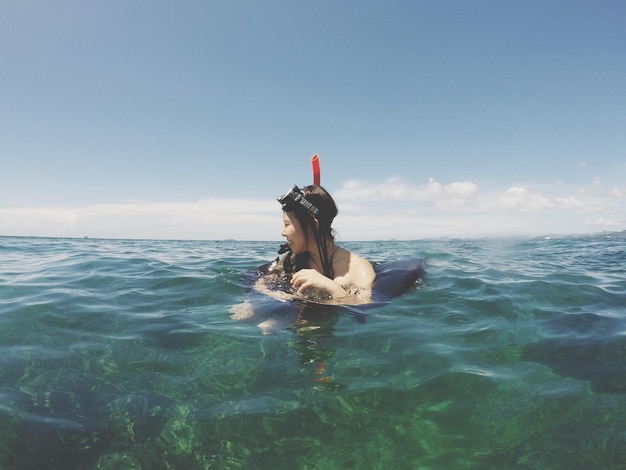 Photo une femme nageant dans la mer contre le ciel