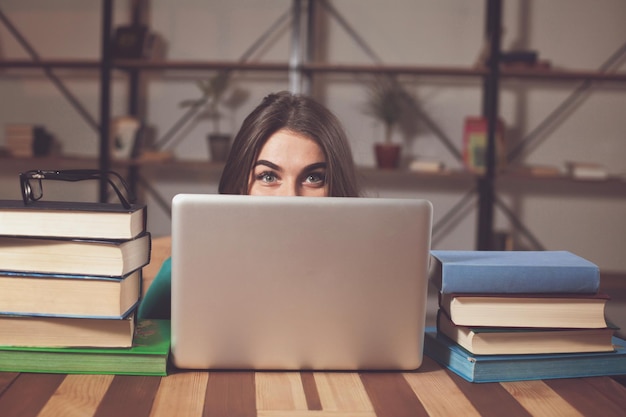 Une femme ne montre que ses yeux en regardant par son ordinateur portable