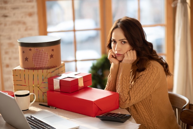 Femme ne se sentant pas satisfaite après avoir emballé des cadeaux