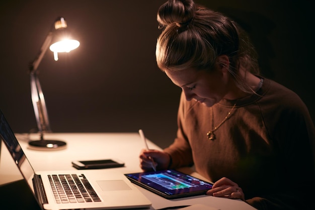 Femme négociant en actions au bureau avec les données sur les prix des actions affichées sur un ordinateur portable et une tablette numérique