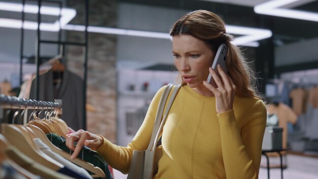 Une femme nerveuse faisant ses courses en appelant au téléphone portable dans un magasin de vêtements coûteux.