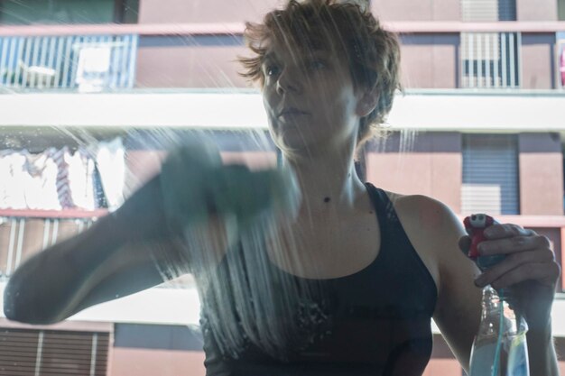 Photo une femme nettoie une fenêtre en verre.