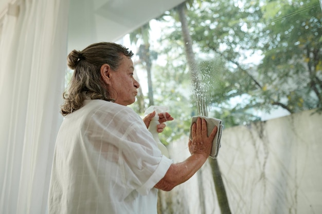 Une femme nettoie les fenêtres de la maison.