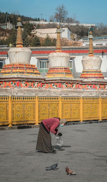 Une femme nettoie une marmite d'eau devant un temple.