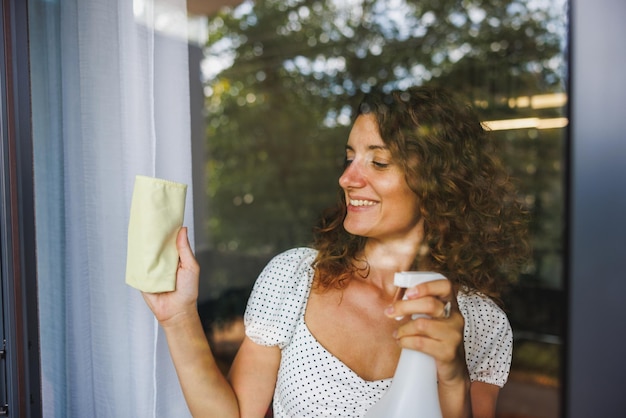 Une femme nettoie les vitres des fenêtres