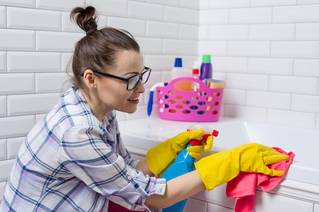 Femme nettoyant la baignoire avec un chiffon