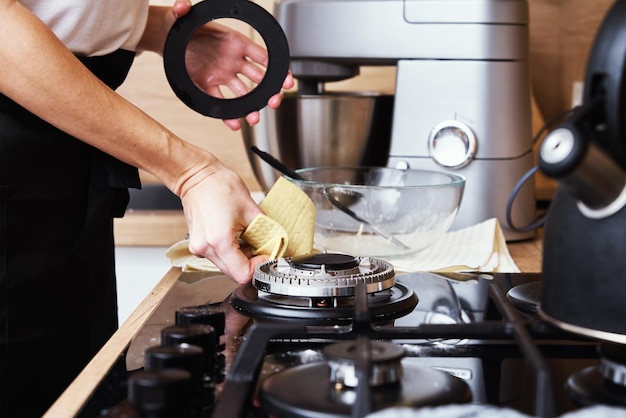 Femme nettoyant une cuisinière à gaz à l'intérieur de la cuisine