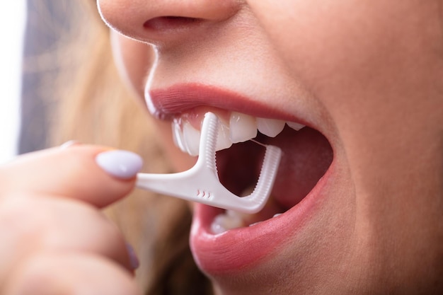 Femme nettoyant les dents avec du fil dentaire