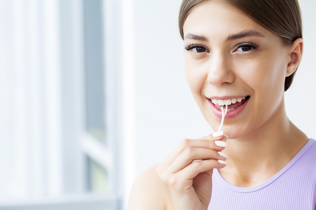 Femme nettoyant les dents avec du fil dentaire