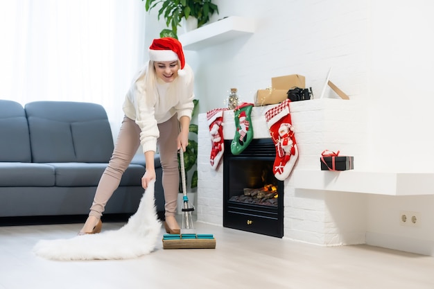 Femme nettoyant la maison. Fille drôle dans le chapeau d'assistant de santa. Concept de temps de Noël et de travaux ménagers.