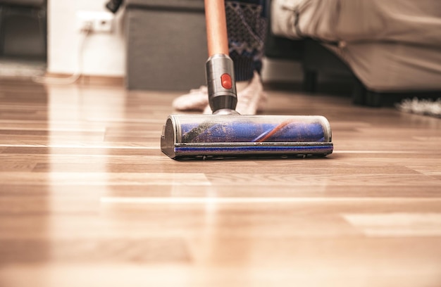 Femme nettoyant le sol à l'aide d'un aspirateur à la maison