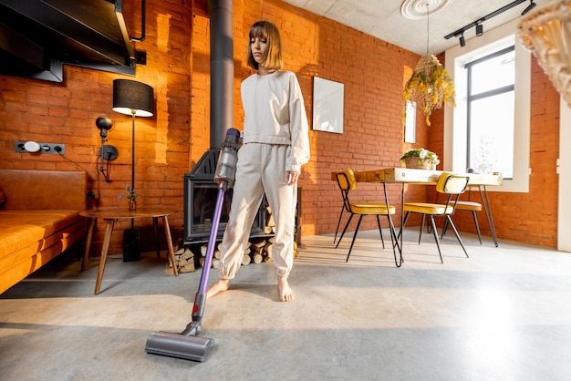 Femme nettoyant le sol avec un aspirateur à main