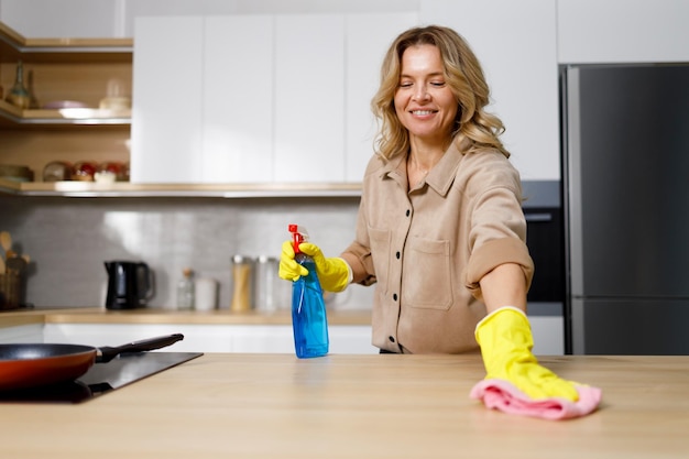 Femme nettoyant la table de la cuisine avec du détergent et du chiffon Femme de ménage lavant et désinfectant le comptoir