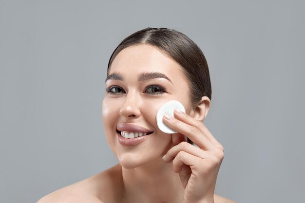 Photo femme nettoyant le visage avec un coussin blanc belle fille enlevant le maquillage coussin de coton cosmétique blanc