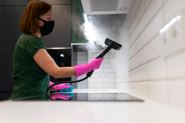 Femme, nettoyer les carreaux dans la cuisine avec machine à vapeur