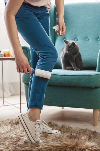 Femme, nettoyer les vêtements avec rouleau collant des poils de chats.