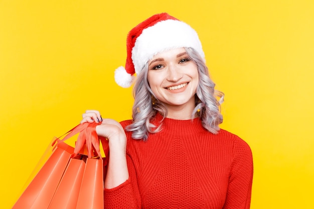 Femme de Noël au chapeau du père Noël tenant un gros sac avec des cadeaux isolés.