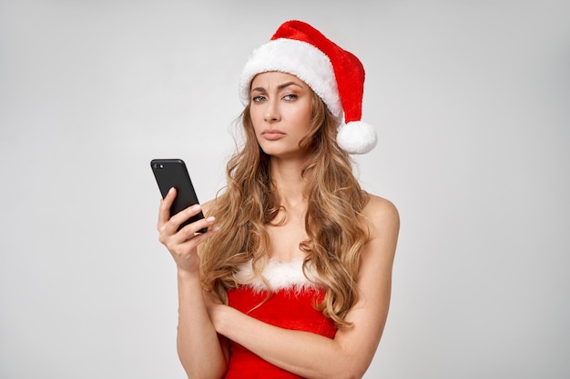 Femme de Noël chapeau de père Noël fond de studio blanc avec smartphone à la main