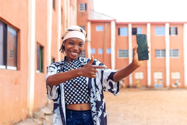 Une femme noire africaine heureuse tenant un téléphone.
