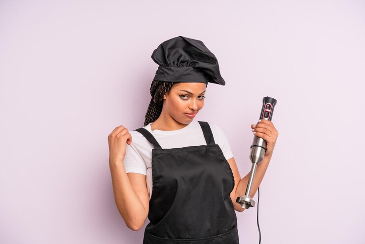 Photo femme noire afro à l'air arrogante, réussie, positive et fière. chef avec mixeur plongeant