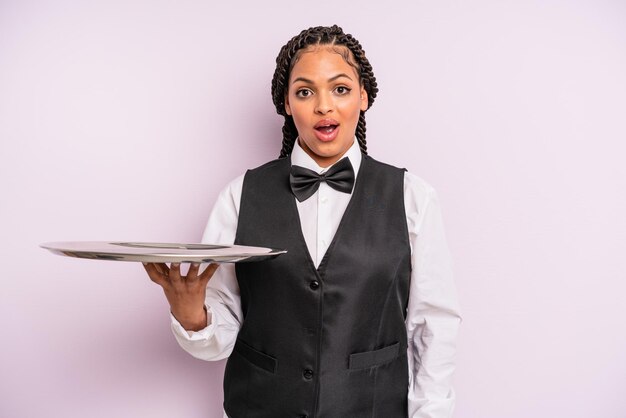 Femme noire afro à la recherche d'un serveur très choqué ou surpris avec un plateau