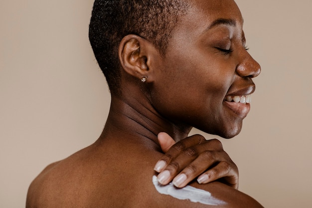 Femme noire appliquant la crème pour le corps