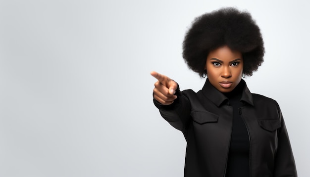 Une femme noire aux cheveux afro pointe un espace de copie sur fond gris pour le concept publicitaire