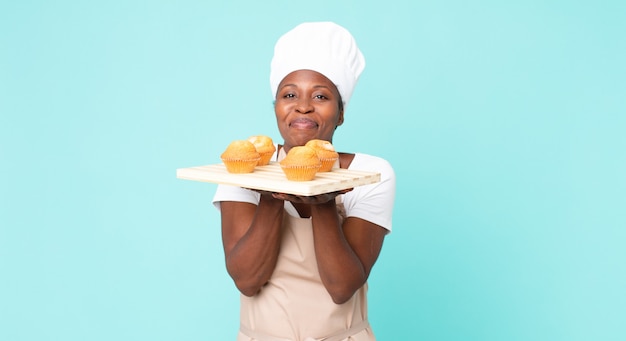 Femme noire de chef d'adulte d'afro-américain tenant un plateau de muffins