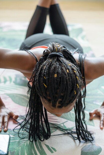 Photo une femme noire avec des cheveux tressés s'entraîne à la maison en faisant des pompes.