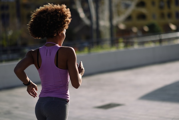 Femme noire, coiffure afro, courir à l&#39;extérieur au coucher du soleil