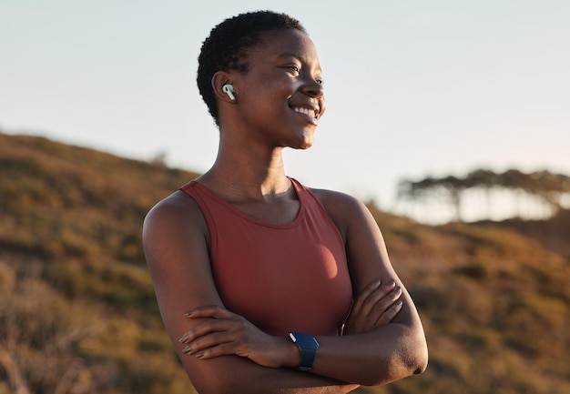 Femme noire coureur sourire et musique avec écouteurs nature et colline pour le bonheur et la paix de remise en forme Diffusion d'exercices en plein air et montre intelligente pour fille en formation course ou aventure de bien-être