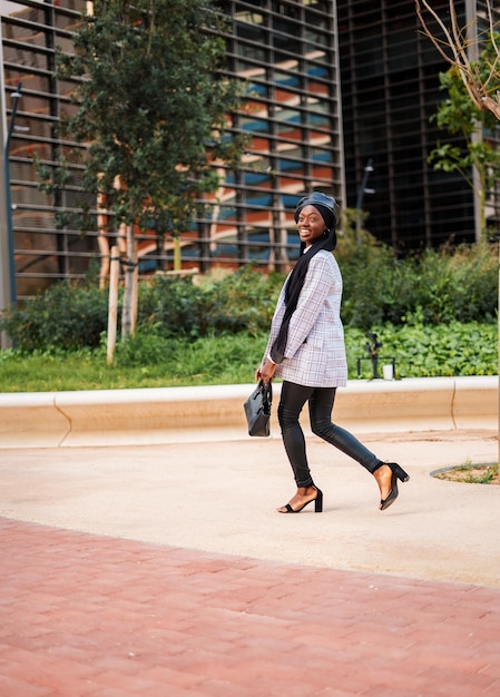 Femme noire élégante profitant d'une agréable promenade dans le parc de la ville