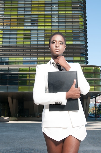 Femme noire exécutive dans le quartier des affaires dans une ville sous un ciel bleu