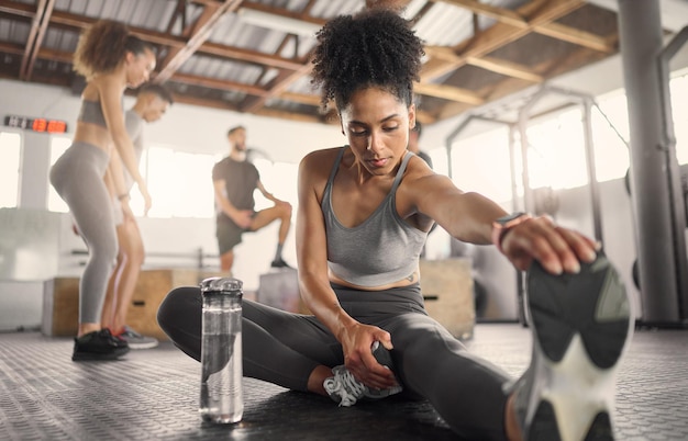 Photo femme noire fitness et étirement dans la salle de gym pour faire de l'exercice ou s'entraîner pour la santé et le bien-être jambes de femme et échauffement pour l'énergie avec des chaussures de sport et une forte performance corporelle