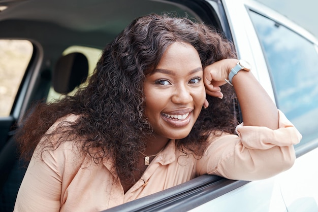 Femme noire heureuse et souriante à la fenêtre de la voiture lors d'un voyage en voiture ou de vacances