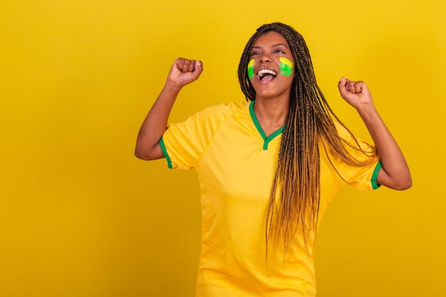 Photo femme noire jeune fan de football brésilien célébrer vibrer et faire la fête danser