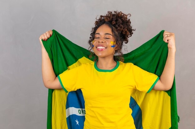 Femme noire jeune fan de football brésilien avec le drapeau du brésil sur un fond neutre avec un espace libre pour le texte