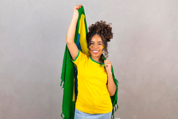 Femme noire jeune fan de football brésilien avec le drapeau du brésil sur un fond neutre avec un espace libre pour le texte