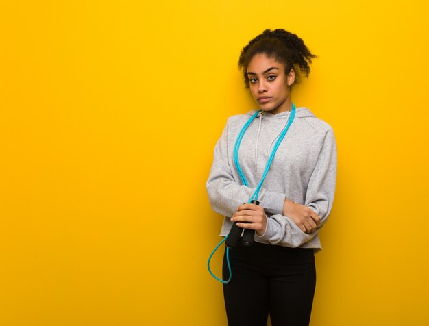 Femme noire jeune fitness regardant droit devant. Tenant une corde à sauter.