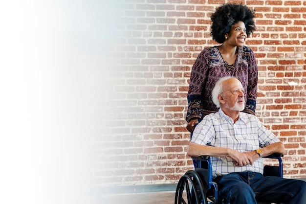 Femme noire poussant le fauteuil roulant de son patient