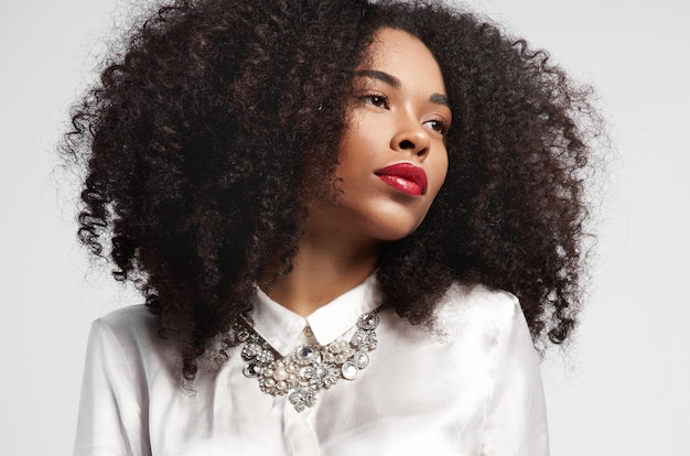 Femme noire regardant de côté avec une peau idéale et des cheveux bouclés