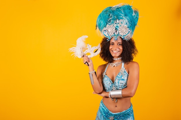 Photo femme noire reine de l'école de samba brésilienne avec des vêtements de carnaval bleus et une couronne de plumes tenant un masque bras croisés