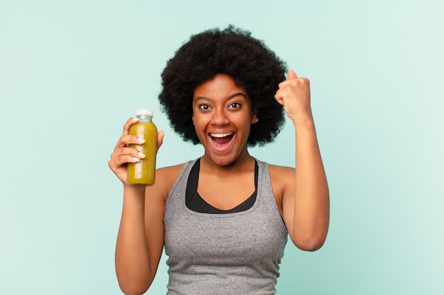 Femme noire de remise en forme afro avec un smoothy