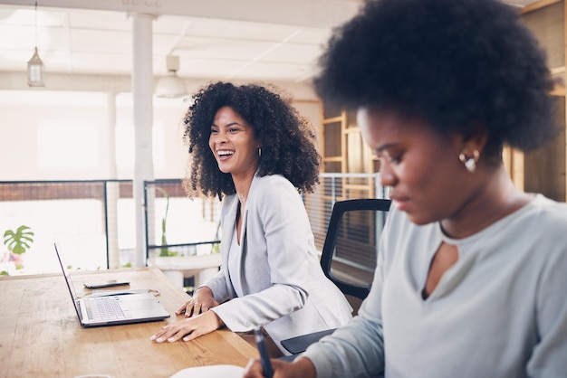 Femme noire riant lors d'une réunion d'affaires pour des idées amusantes de planification en ligne et de démarrage du travail d'équipe dans l'espace de travail de bureau Des professionnels heureux travaillant sur un ordinateur portable pour la collaboration et le flux de travail de carrière