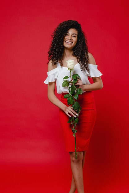 Femme noire, à, rose blanche, sourire, sur, mur rouge