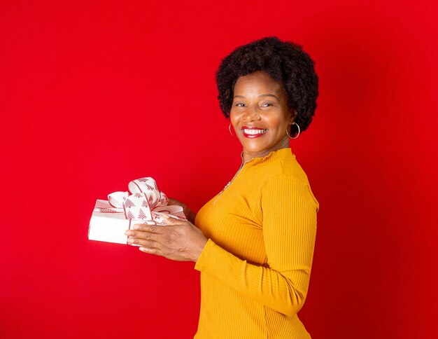 Femme noire souriante et tenant une boîte-cadeau dans les mains