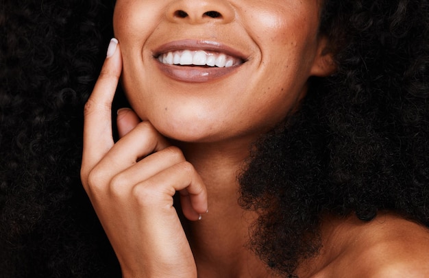 Une femme noire sourit et touche le visage avec une fierté de beauté naturelle et confiante avec des cheveux bouclés Cosmétiques Femme et jeune femme afro-américaine avec soin du visage heureux et bio avec une peau lisse